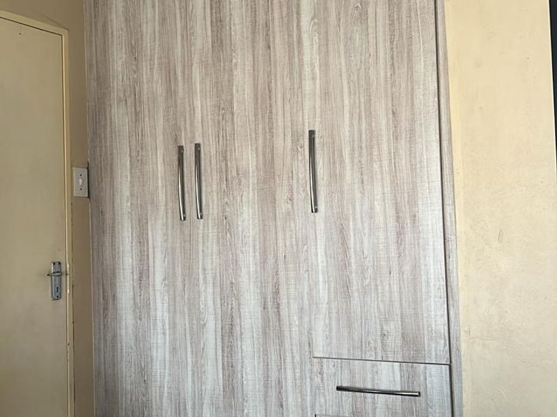 A bedroom featuring modern wood-grain built-in cupboards with integrated drawers and recessed ceiling lighting.