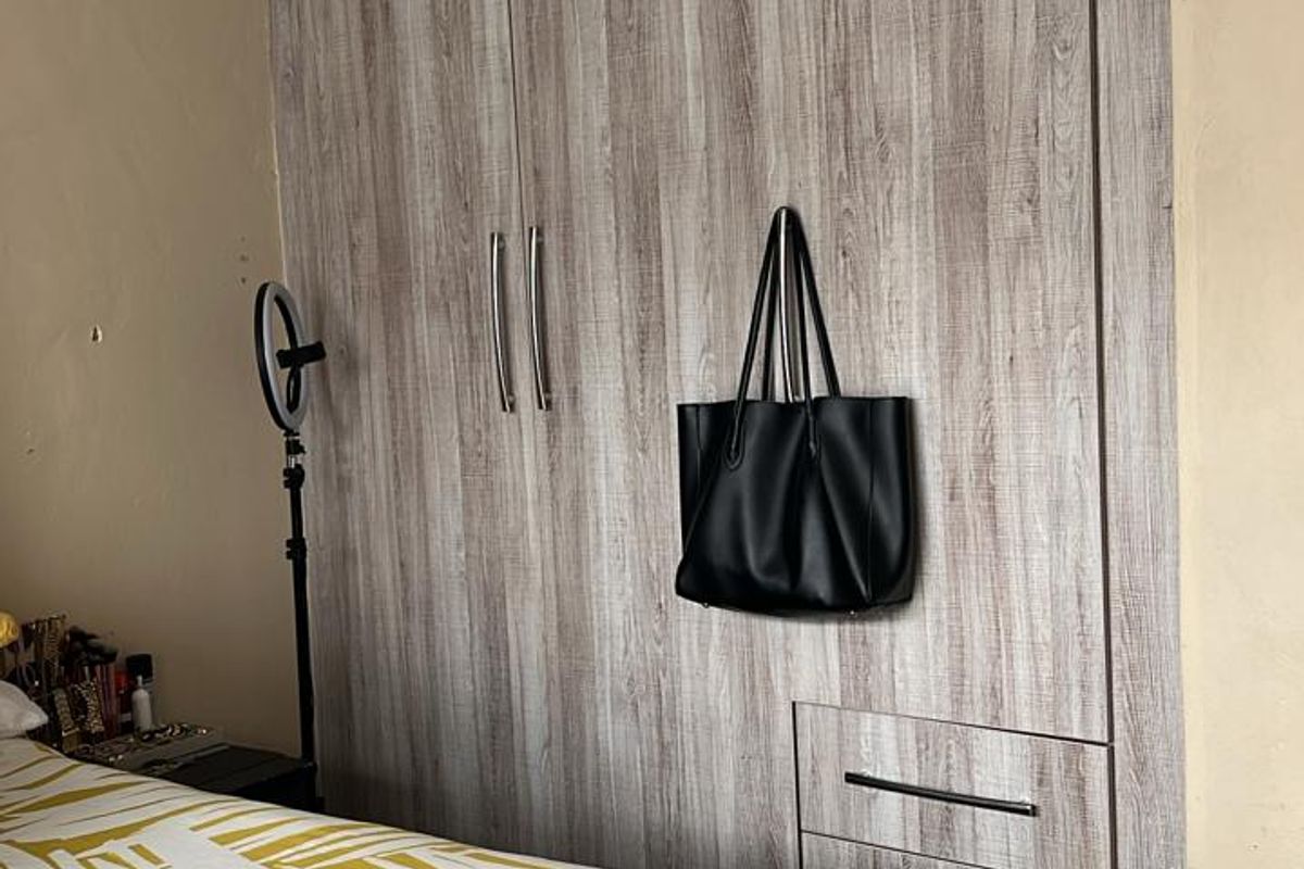 A bedroom featuring modern wood-grain built-in cupboards with integrated drawers and recessed ceiling lighting.