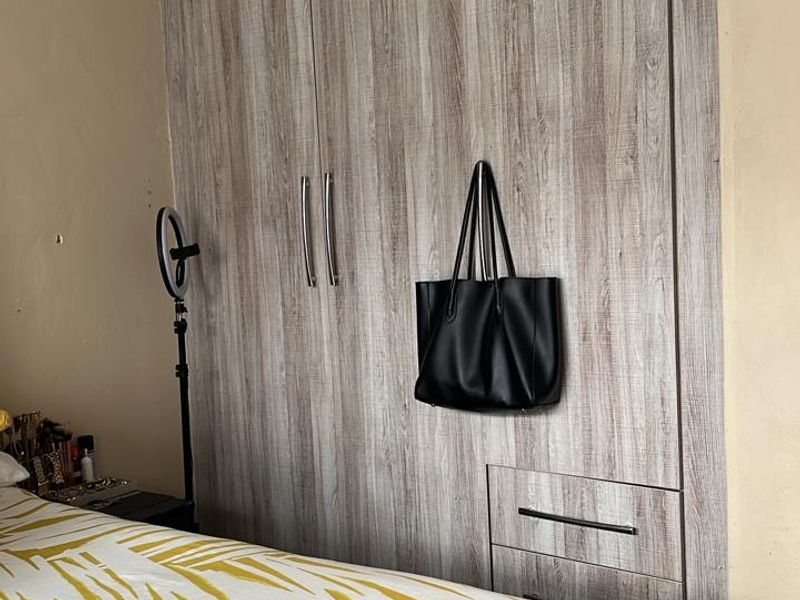 A bedroom featuring modern wood-grain built-in cupboards with integrated drawers and recessed ceiling lighting.