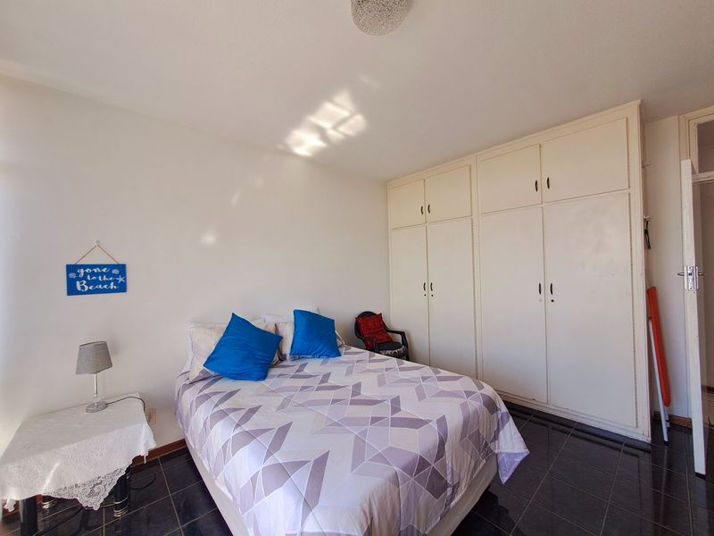 A bedroom featuring built-in cupboards and dark tiled flooring, offering a functional space with ample storage.