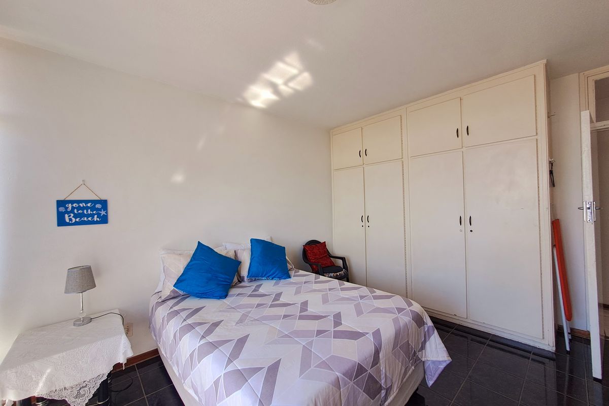 A bedroom featuring built-in cupboards and dark tiled flooring, offering a functional space with ample storage.