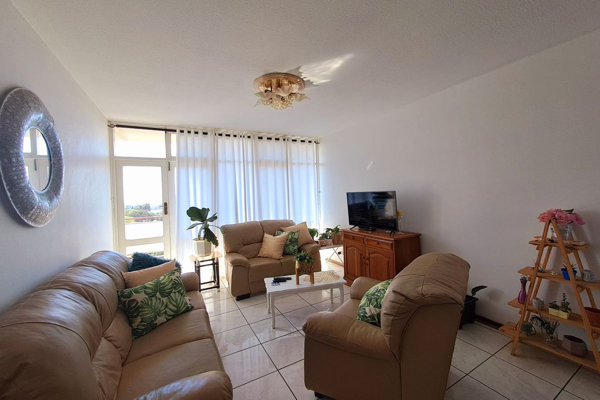 A bright living room featuring tiled flooring and a glass sliding door leading to an outdoor area, providing natural light throughout the space.