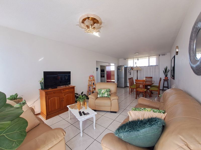 An open-plan living and dining area featuring ceramic floor tiles and natural light, providing a functional space for relaxation and meals.