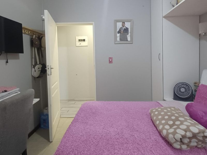 A bedroom featuring a built-in wardrobe, neutral wall finishes, and an internal door leading to an adjacent space.