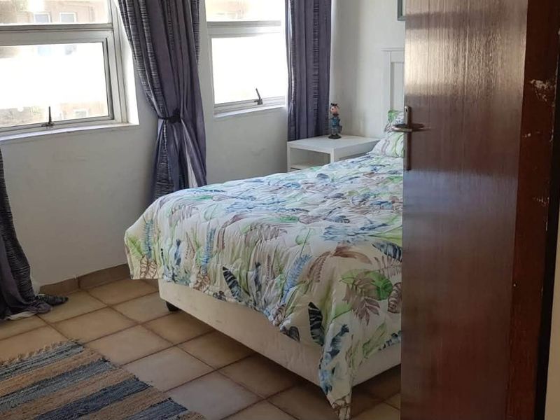 A functional bedroom featuring tiled flooring and large windows that provide natural light.