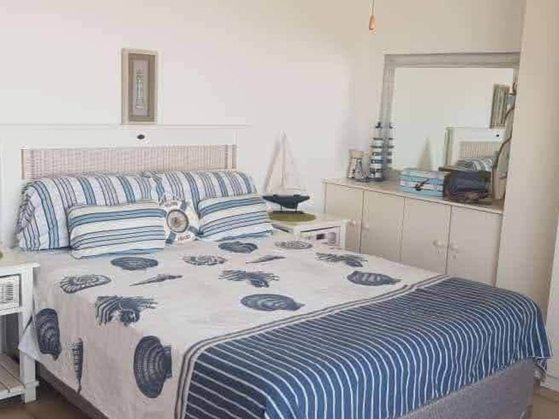 A bedroom featuring tiled flooring and a built-in wardrobe, offering a functional space with neutral finishes.