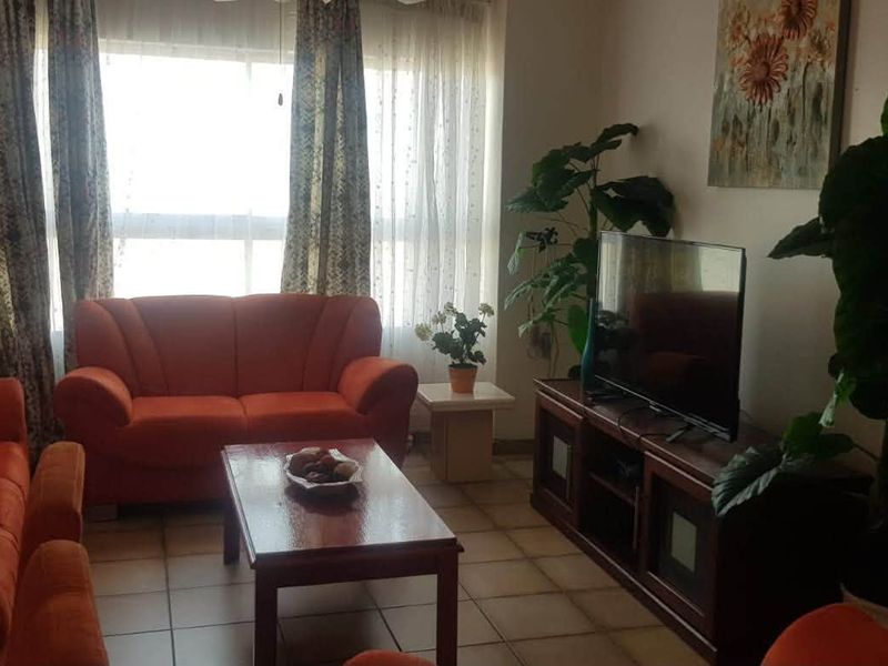 A comfortable living room featuring tiled flooring and a large window that allows for natural light.