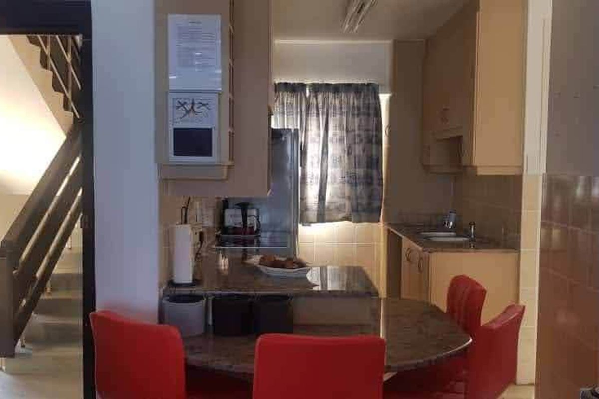 A functional kitchen area featuring granite countertops, built-in cabinetry, and a tiled backsplash, adjacent to a staircase entrance.