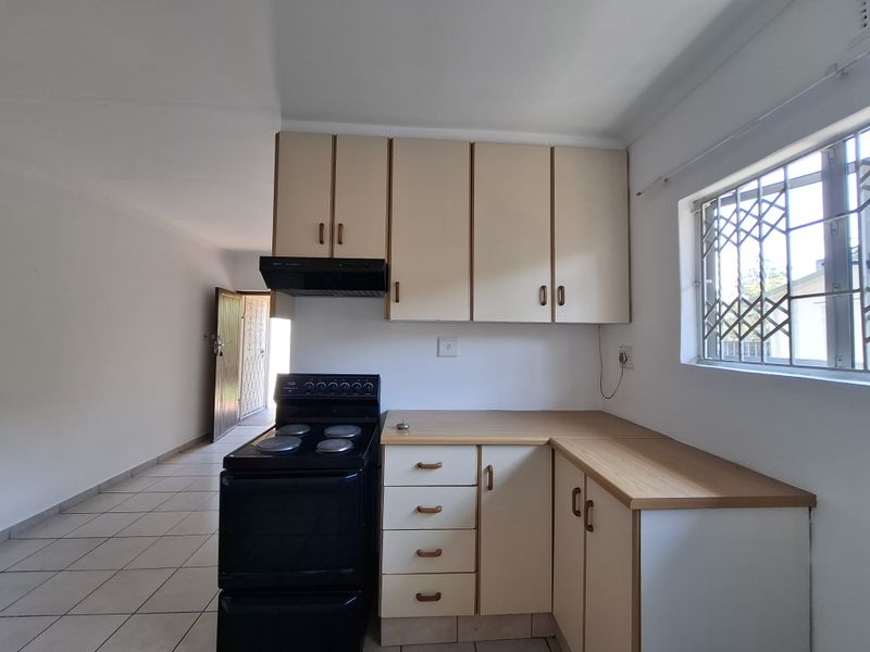 A functional kitchen featuring built-in cabinetry, laminate countertops, a freestanding stove with extractor fan, and tiled flooring, offering a clean and practical workspace.