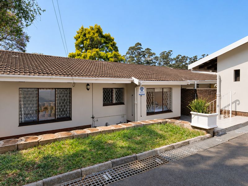 Front exterior view of the townhouse featuring a tiled roof, security-barred windows, and a paved driveway with integrated drainage.