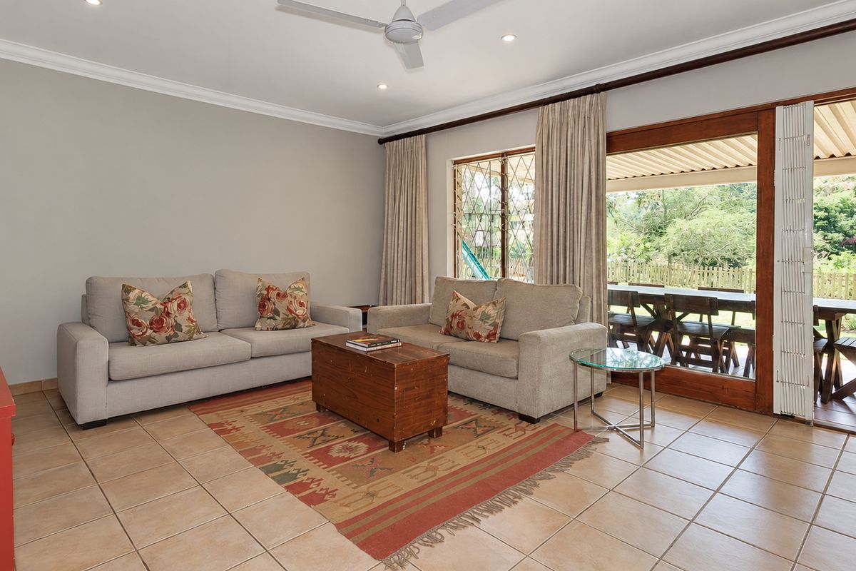 A comfortable living room featuring tiled flooring, recessed lighting, a ceiling fan, and large sliding glass doors providing direct access to the outdoor patio area.
