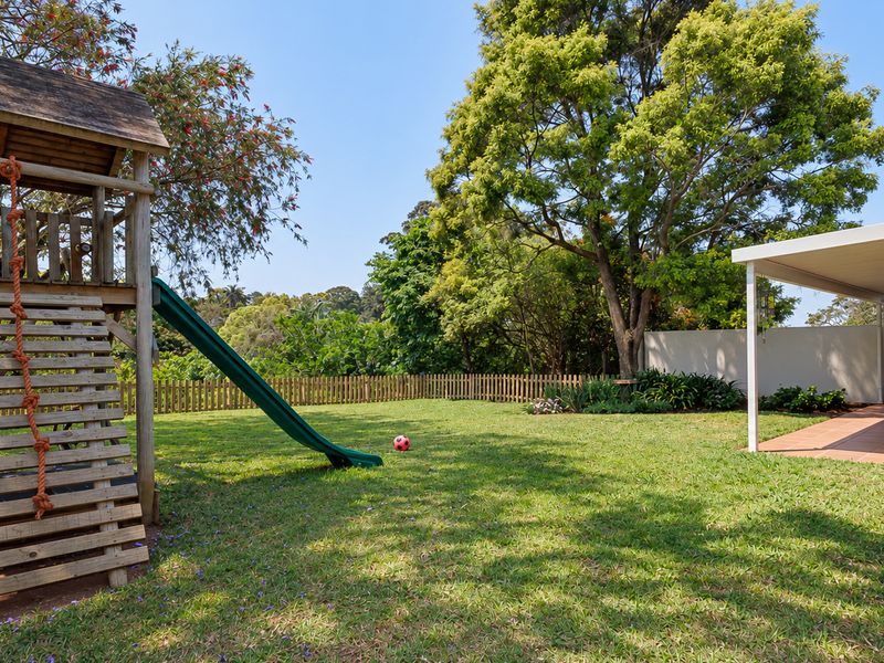 Spacious rear garden featuring a covered patio area, established trees, and a secure boundary fence, ideal for outdoor relaxation and family activities.