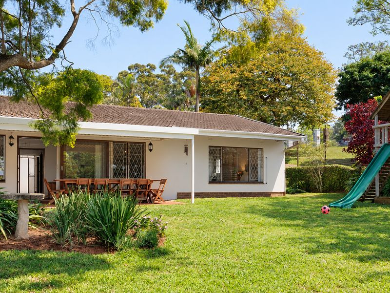 Rear view of the townhouse featuring a covered patio, established garden, and tiled roof structure.