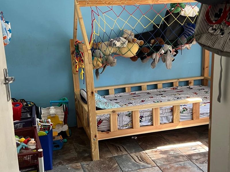 A bedroom featuring tiled flooring and a wooden bed frame, currently utilized as a child's room.