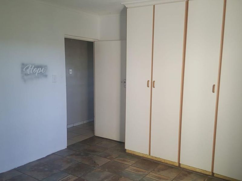 A bedroom featuring built-in cupboards and tiled flooring, requiring cosmetic updates to the walls and cupboard base trim.