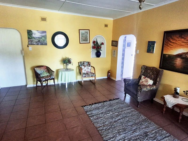 A spacious living area featuring tiled flooring, an arched doorway, and a built-in wall niche, offering a functional layout with potential for modern updates.