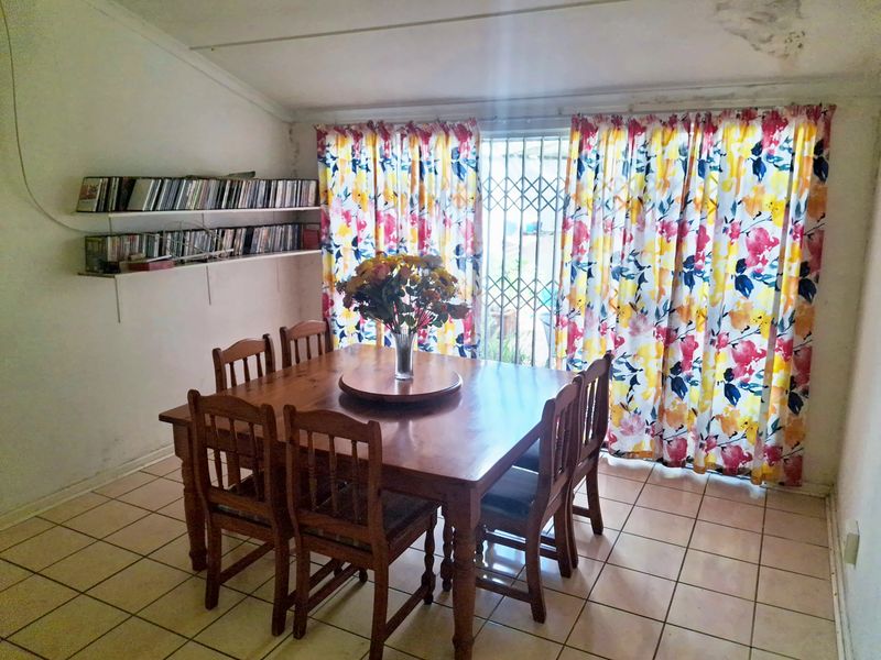 Dining area featuring tiled flooring, built-in shelving, and a security gate leading to the exterior. The space requires cosmetic updates to the ceiling and walls.