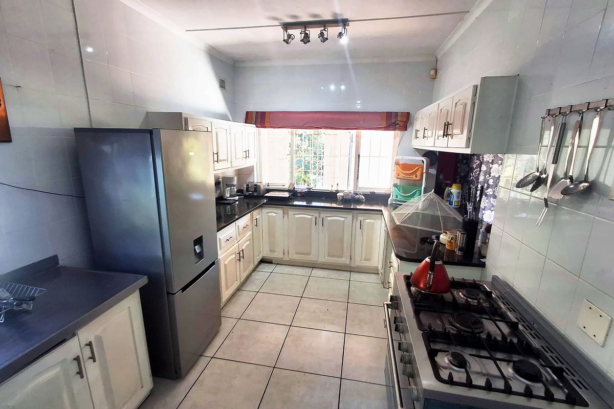 Functional kitchen featuring built-in cabinetry, granite countertops, gas hob, oven, and tiled finishes throughout.
