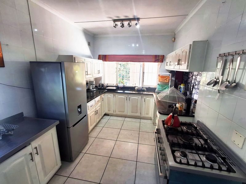 Functional kitchen featuring built-in cabinetry, granite countertops, gas hob, oven, and tiled finishes throughout.