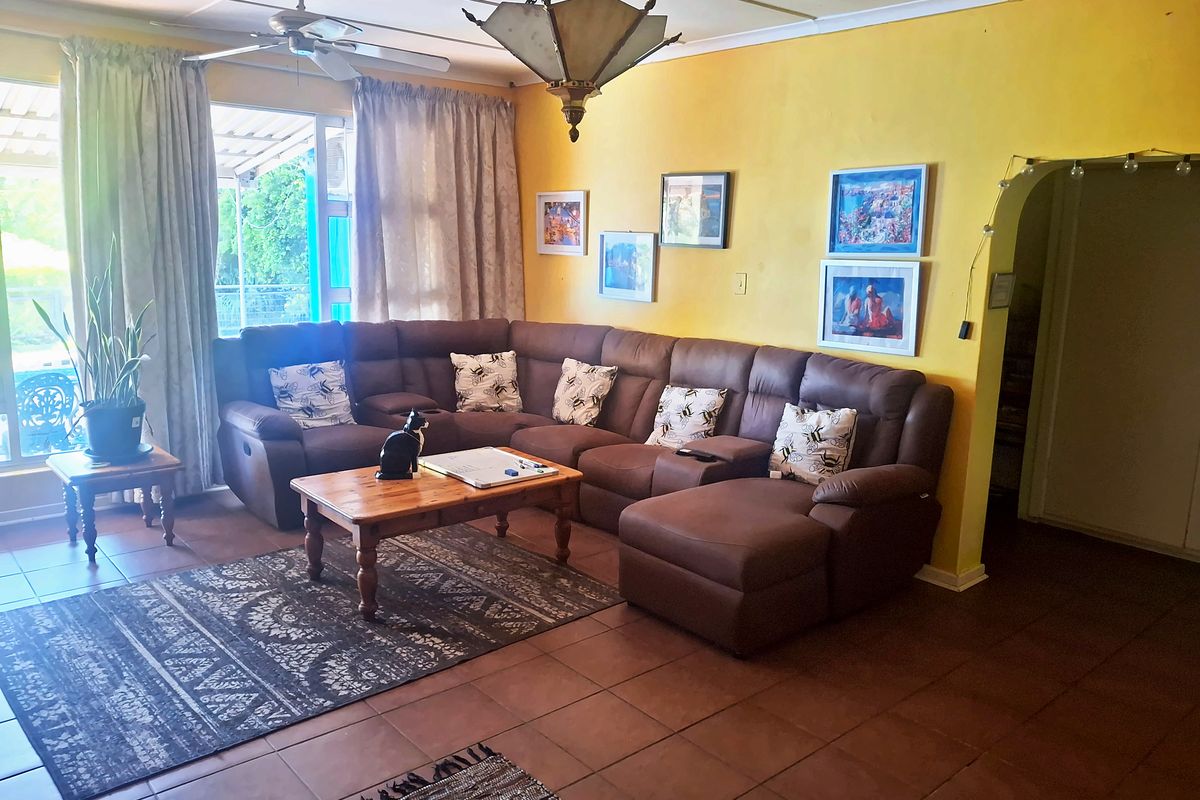 A spacious living room featuring tiled flooring, a ceiling fan, and an arched doorway leading to adjacent areas, with access to an outdoor patio.