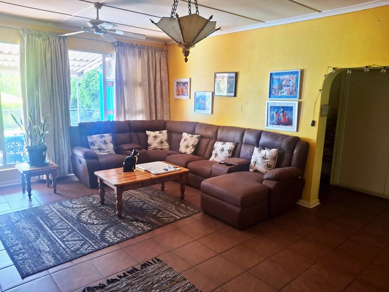 A spacious living room featuring tiled flooring, a ceiling fan, and an arched doorway leading to adjacent areas, with access to an outdoor patio.