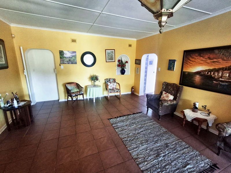 Spacious living area featuring traditional tiled flooring, arched doorways, and a built-in wall niche, offering a classic layout with potential for modernization.