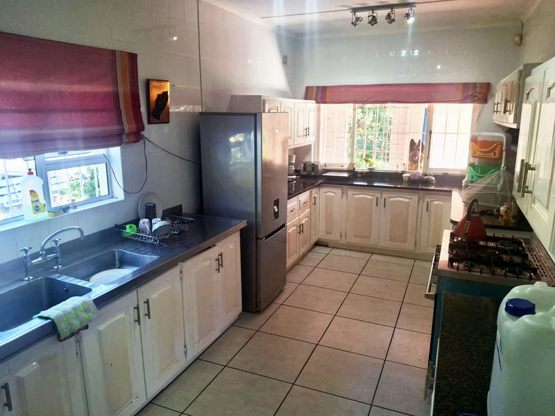 A functional kitchen featuring built-in cabinetry, a double basin sink, gas hob, and tiled surfaces throughout, offering a practical layout for daily use.