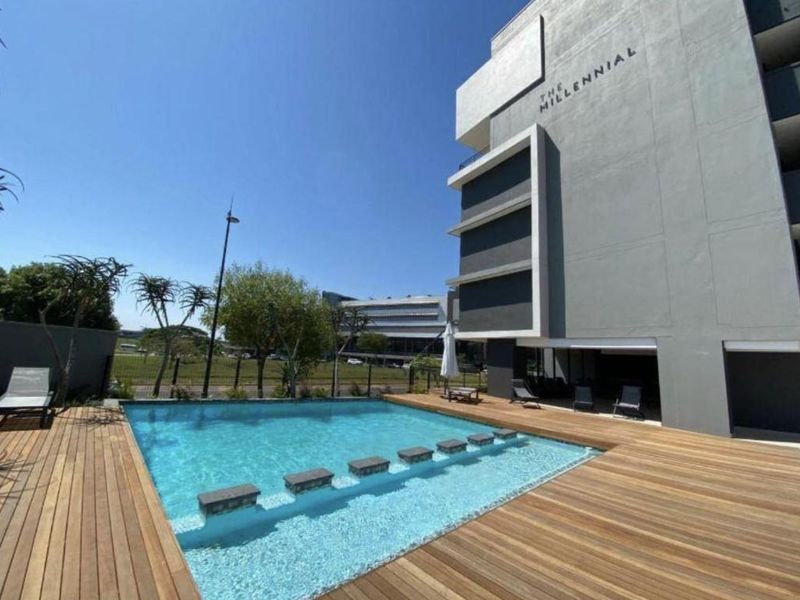 Modern apartment complex pool area featuring a swimming pool with integrated stepping stones and extensive timber decking.