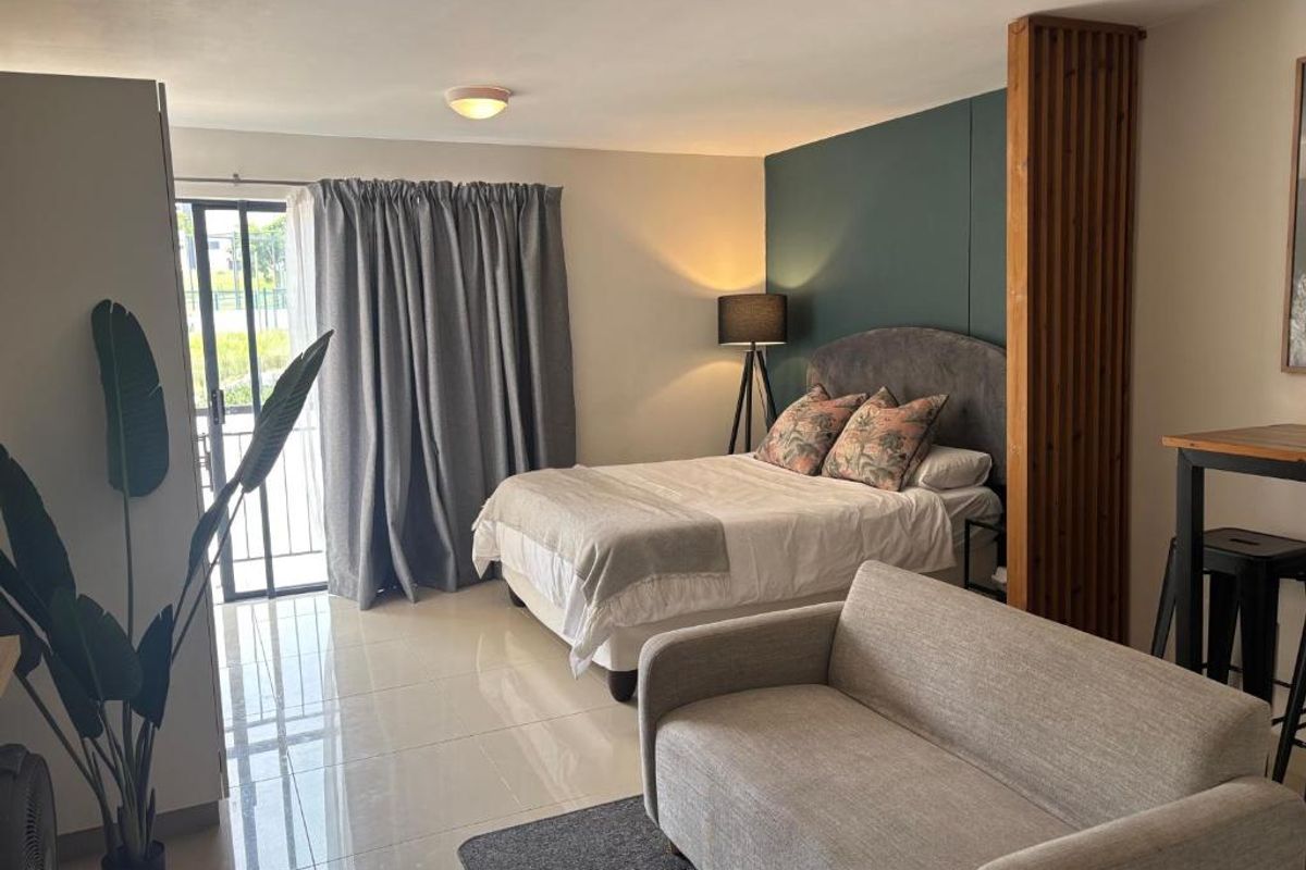 A well-maintained bedroom featuring tiled flooring, a modern accent wall, and a timber slat divider, with direct access to a balcony via sliding doors.