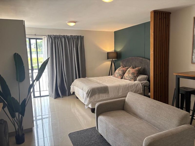 A well-maintained bedroom featuring tiled flooring, a modern accent wall, and a timber slat divider, with direct access to a balcony via sliding doors.