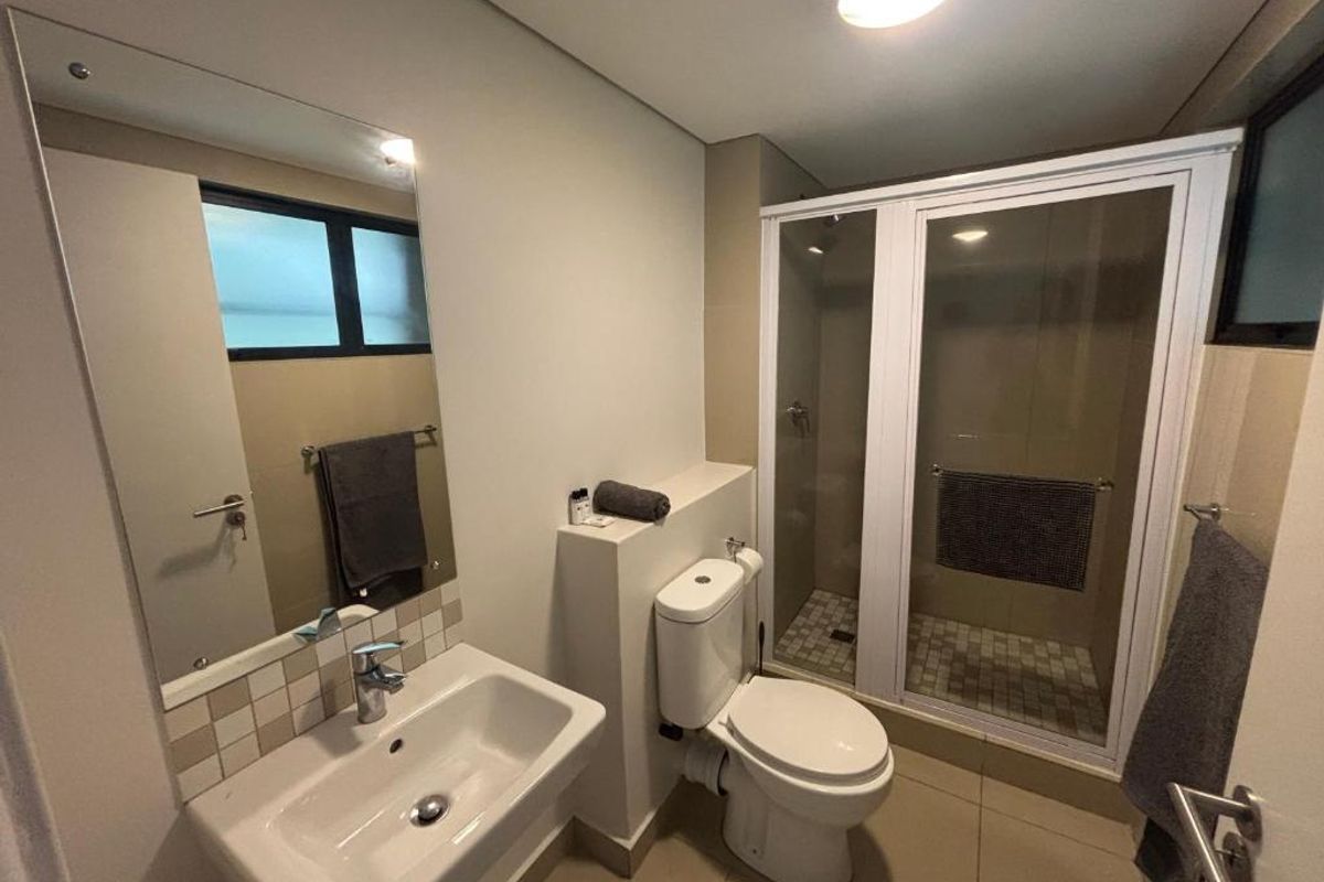 A clean and functional bathroom featuring a wall-mounted basin, a toilet, and a separate shower enclosure with tiled finishes.