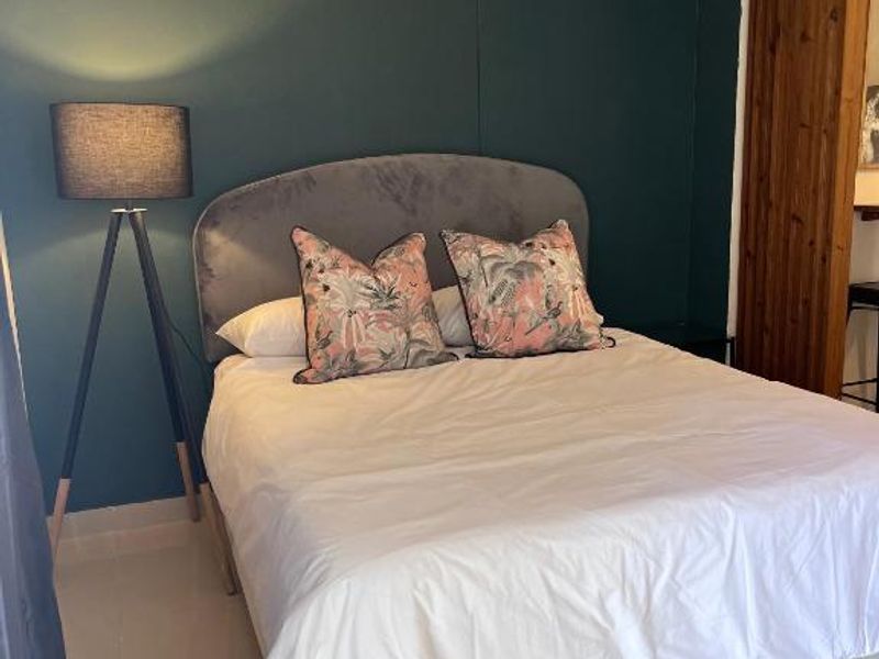 A cozy bedroom featuring a dark accent wall, neutral tiled flooring, and a decorative timber slat room divider.