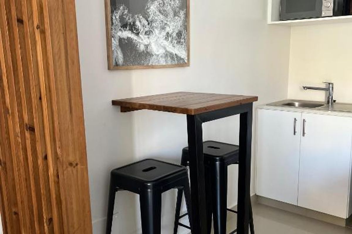 Compact kitchenette featuring white cabinetry, a stainless steel sink with mixer tap, and a dedicated built-in microwave shelf.