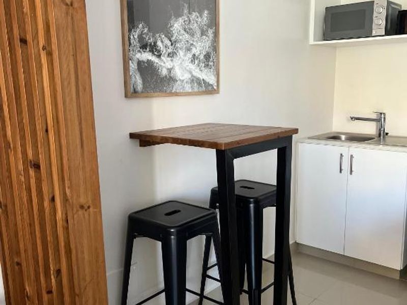 Compact kitchenette featuring white cabinetry, a stainless steel sink with mixer tap, and a dedicated built-in microwave shelf.
