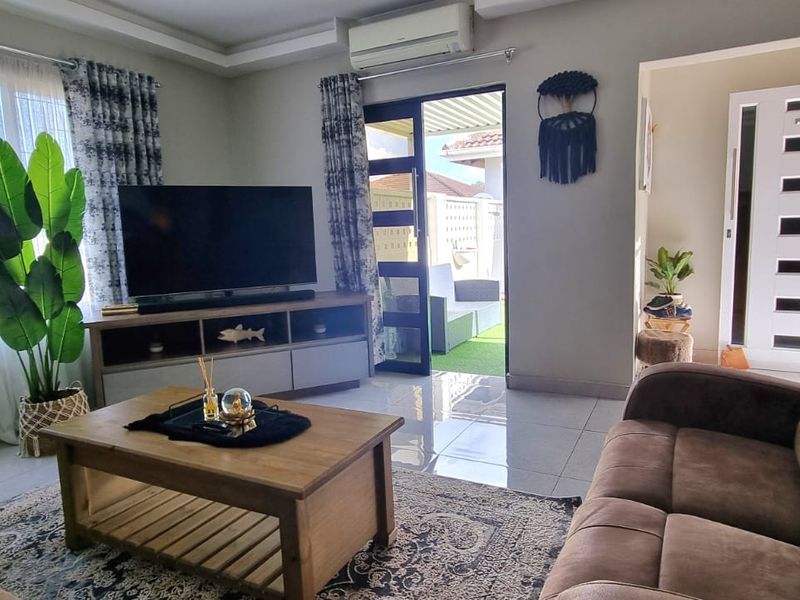 A well-maintained living room featuring tiled flooring, recessed ceiling detail, and direct access to an outdoor patio area through a sliding glass door.