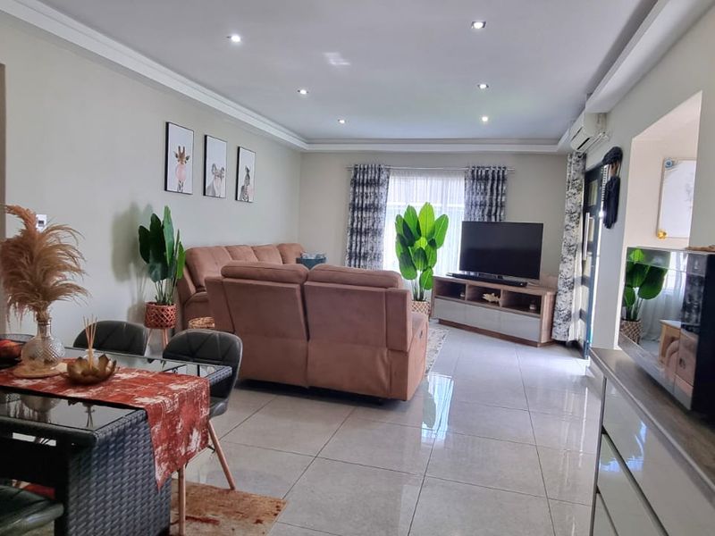 Spacious open-plan living and dining area featuring modern tiled flooring, recessed downlighting, and a wall-mounted air conditioning unit.