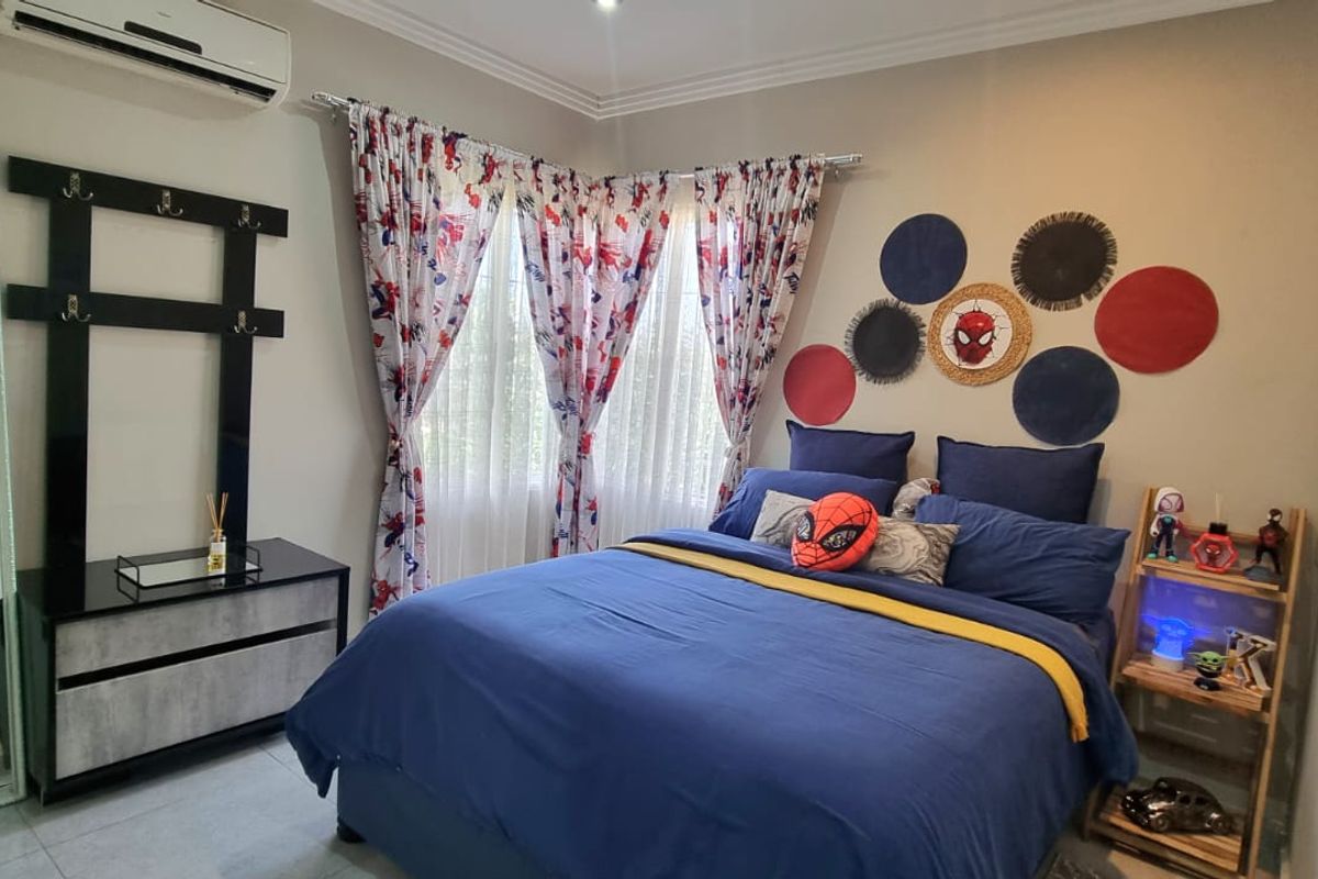 A well-maintained bedroom featuring tiled flooring, cornice detailing, and a wall-mounted split-system air conditioner.