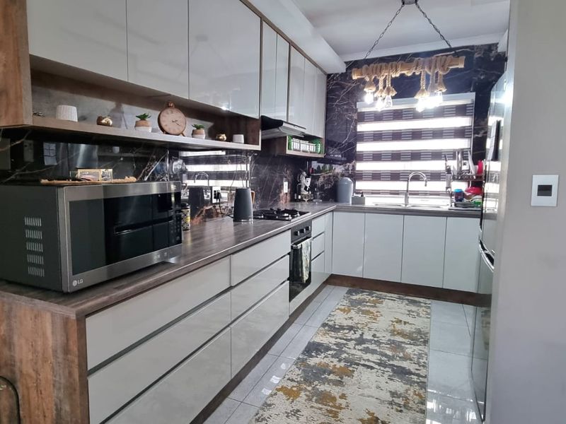Modern kitchen featuring high-gloss cabinetry, dark marble-effect splashbacks, integrated appliances, and a functional layout with ample counter space.