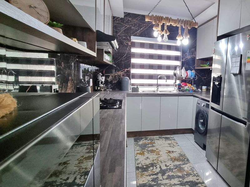 Modern kitchen featuring sleek white cabinetry, dark marble-effect splashbacks, laminate countertops, and integrated appliances, offering a contemporary and functional cooking space.