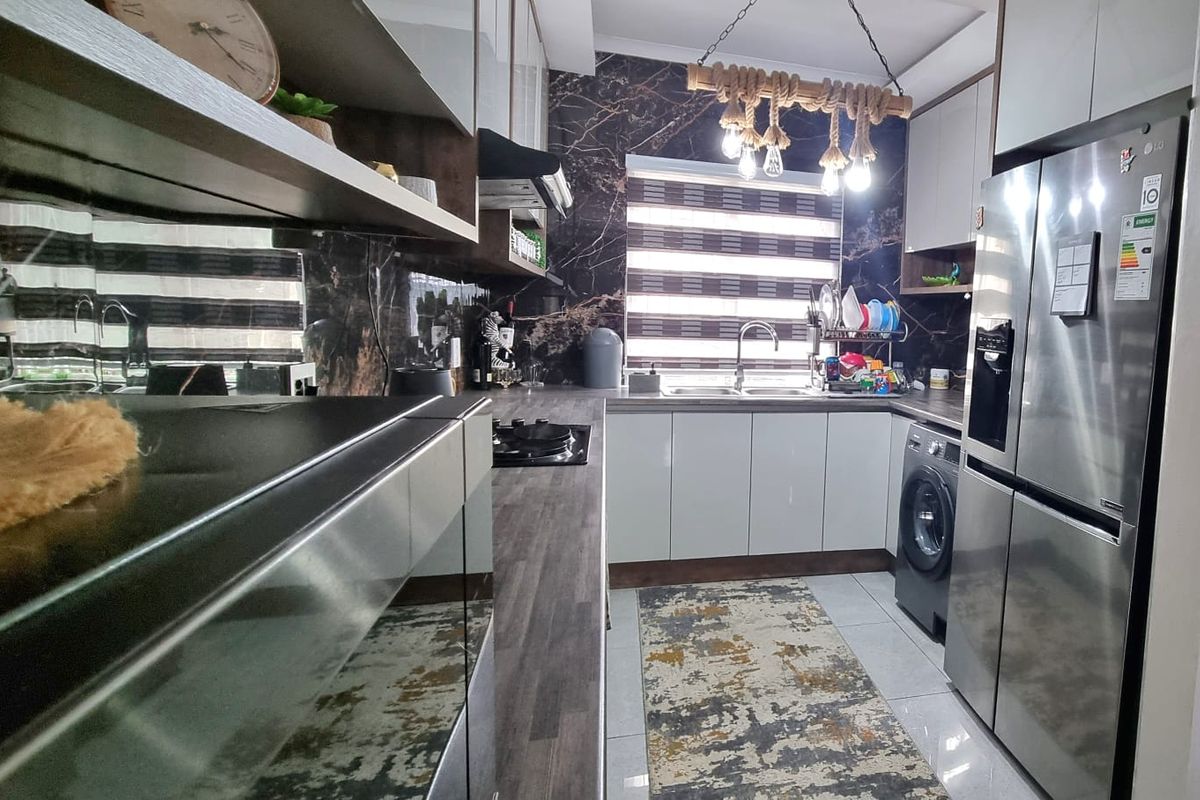 Modern kitchen featuring sleek white cabinetry, dark marble-effect splashbacks, laminate countertops, and integrated appliances, offering a contemporary and functional cooking space.