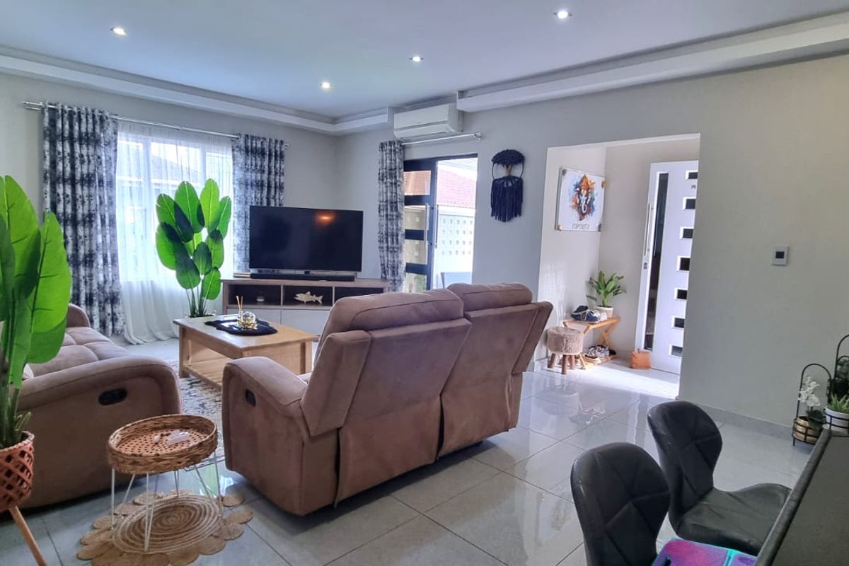 A well-maintained living room featuring tiled flooring, recessed ceiling lighting, and an integrated air conditioning unit, providing a comfortable and bright living space.
