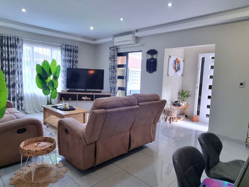 A well-maintained living room featuring tiled flooring, recessed ceiling lighting, and an integrated air conditioning unit, providing a comfortable and bright living space.