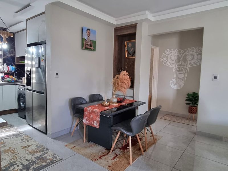 An open-plan living and dining area featuring modern tiled floors, recessed ceiling details, and a functional kitchen space with built-in cabinetry.