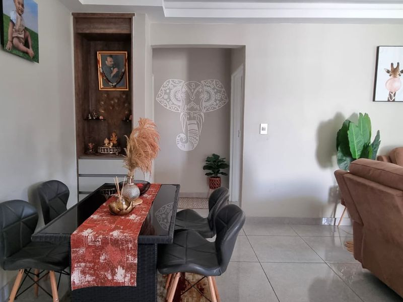 An open-plan living and dining area featuring tiled flooring, coved ceilings, and a built-in recessed display niche.