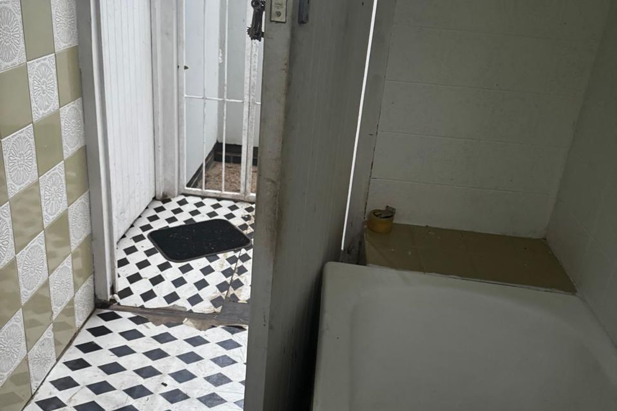 A dated bathroom featuring a bathtub and classic checkered floor tiles, requiring renovation to update the finishes and address visible wear.