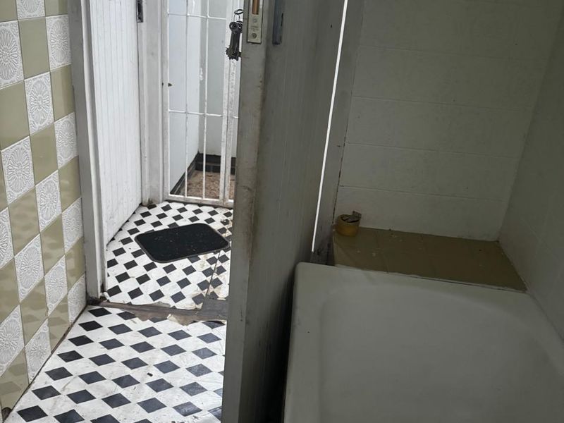 A dated bathroom featuring a bathtub and classic checkered floor tiles, requiring renovation to update the finishes and address visible wear.