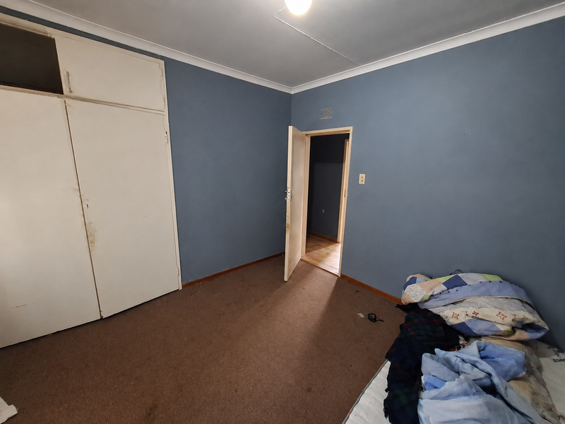 A bedroom featuring built-in cupboards, carpet flooring, and coved ceilings, offering a blank canvas for renovation and modernization.