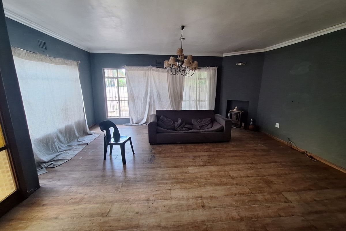 Spacious living room featuring wood-look flooring, a fireplace, and a central chandelier, offering a blank canvas for personalization.
