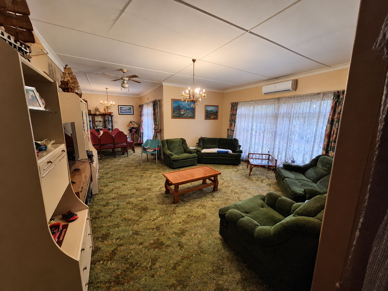 Spacious open-plan living and dining area featuring a split-system air conditioner, ceiling fan, and built-in cabinetry, offering significant potential for modern renovation.