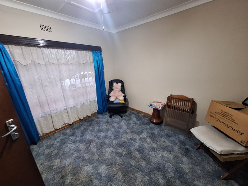 A bedroom featuring neutral wall tones, ceiling cornicing, and blue patterned carpet flooring, offering a blank canvas for potential interior updates.